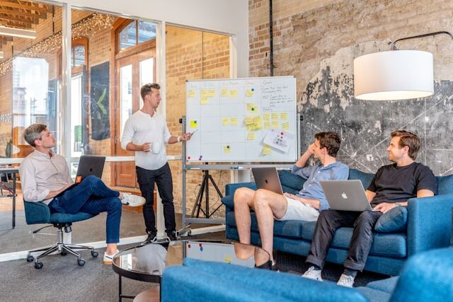  starting a business in Dubai - A team meeting in a modern office with one person presenting at a whiteboard and three others listening.