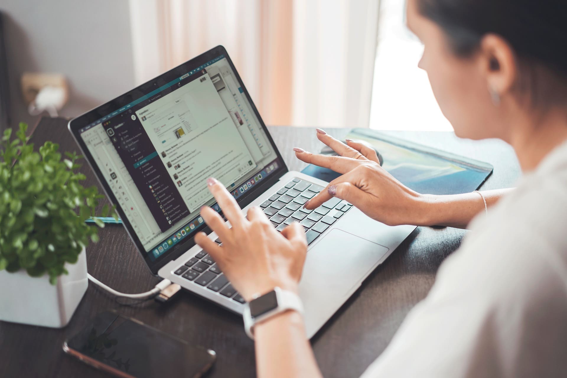 Offshore Business Setup - Person using a laptop with emails on screen, smartphone and plant on the table.