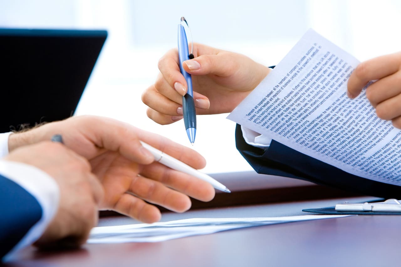 Dubai Company Setup - Two professionals reviewing a document at a desk, with pens in hand.