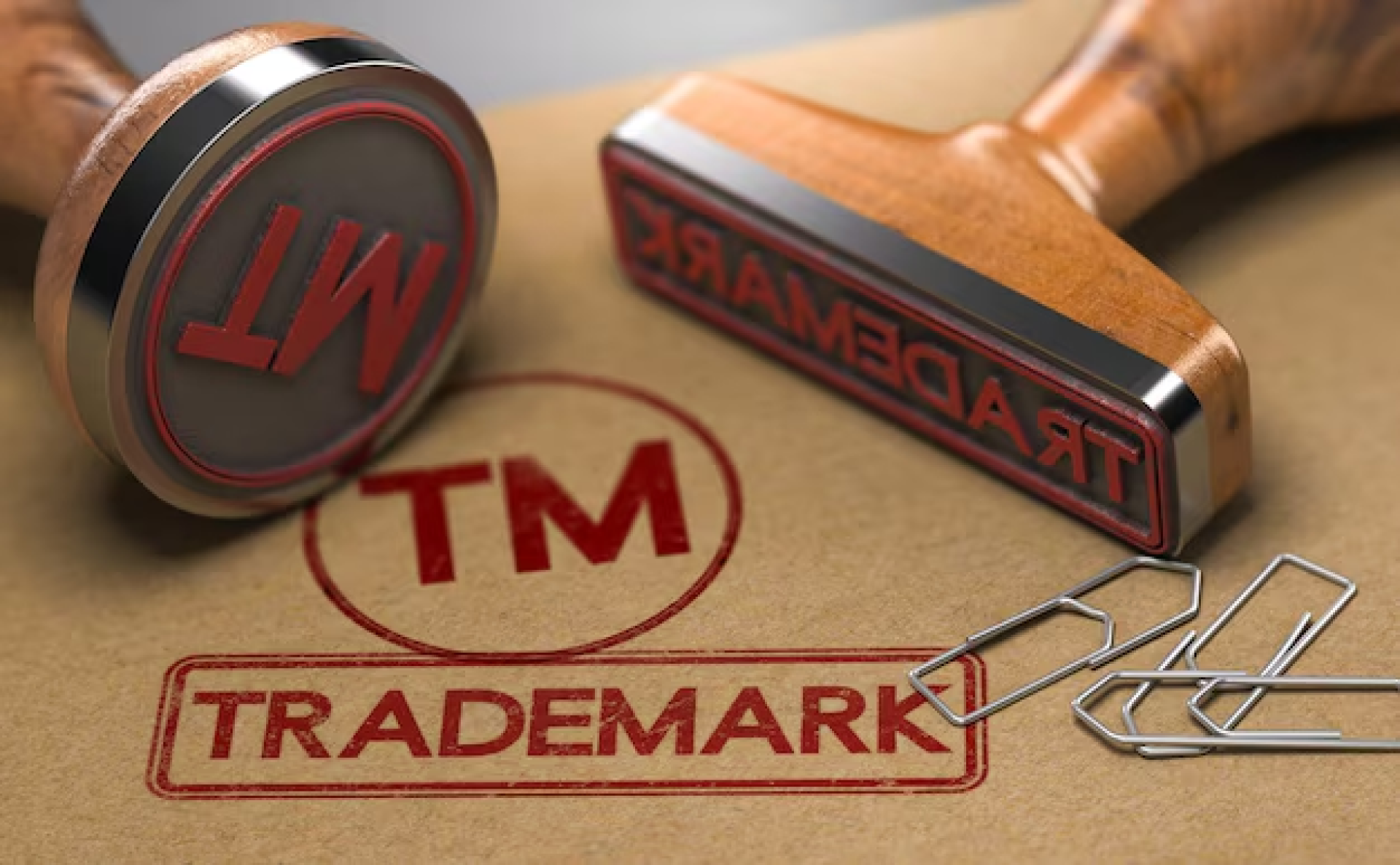 Trademark Registration in Dubai - Two rubber stamps and paper clips on a document marked with a red 'TM' for trademark.